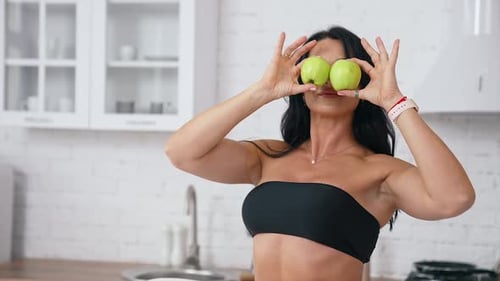 Woman in kitchen ready to prepare meal with vegetables and fruits.