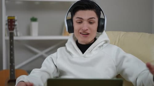 Young Man Video Chatting on Laptop Wearing Headphones