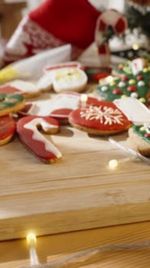 Vertical video. Festive Cookies on Wooden Board with Red Hat and Christmas Tree in Background.