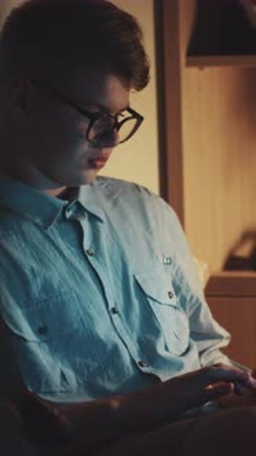 A Young Man in a Blue Shirt Navigates the Digital World with Tech