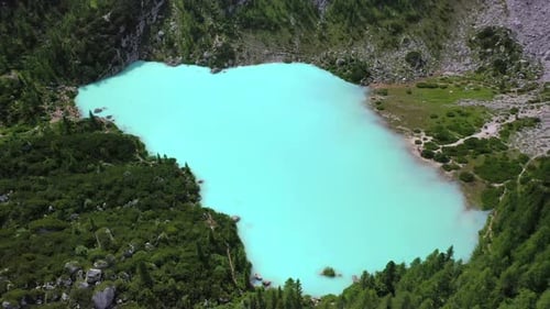 Lake Sorapis bright turqoise water in the Dolomites Italy, rising tilt down aerial