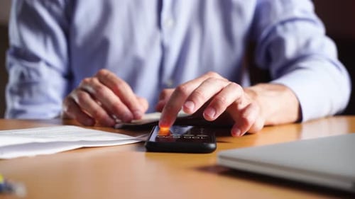 Calculating Money with Phone at Desk