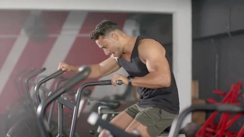 Exercising on stationary bike, man focusing on intense cardio workout in gym