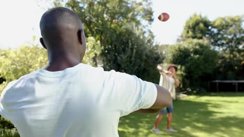 Men Play Catch Football in Green Backyard