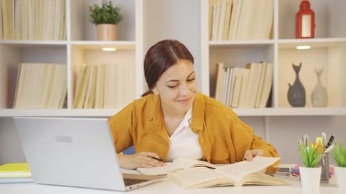 Woman Studying Book and Taking Notes at Desk