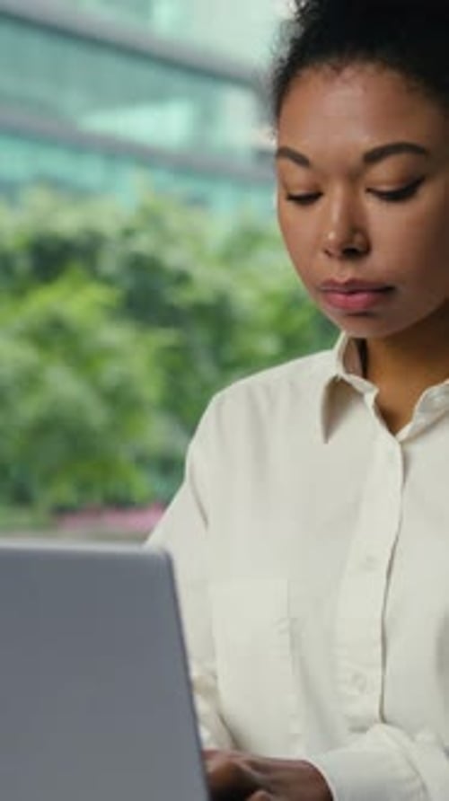 Femme d'affaires afro-américaine concentrée tapant un ordinateur portable dans la ville Femme d'affaires axée sur le travail