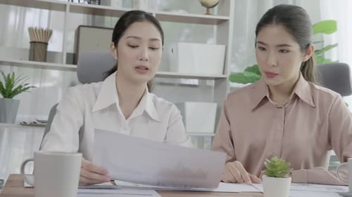 Deux jeunes femmes d'affaires enthousiastes travaillant ensemble dans l'espace de travail de bureau