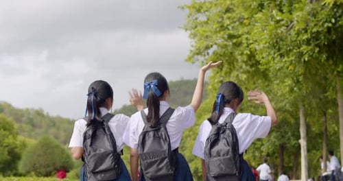 Slow motion back view of a group of happy Asian high school student girls in white uniform