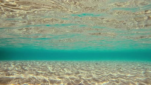 Wellen über dem sandigen Meeresboden mit Reflexion auf der Wasseroberfläche