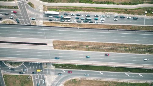 Overhead drone shot of traffic driving over roundabout with highway tunnel underneath, infrastructur