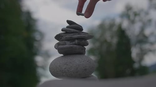 A Man Building a Stone Tower Together Outdoors in Nature Freedom and Carefree Lifestyle