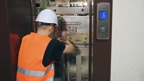 Elevator Mechanic Repairing Inner Workings of Passenger Lift