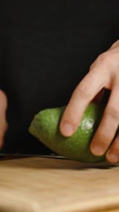 Hands Cut Avocado in Half on Cutting Board
