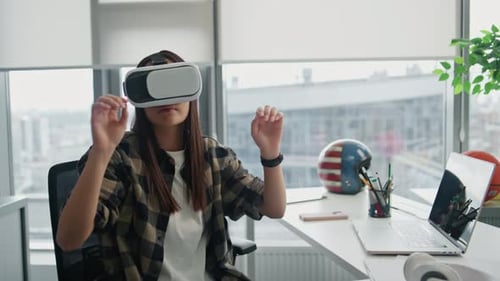 Focused asian programmer replacing vr objects at office with panoramic windows view