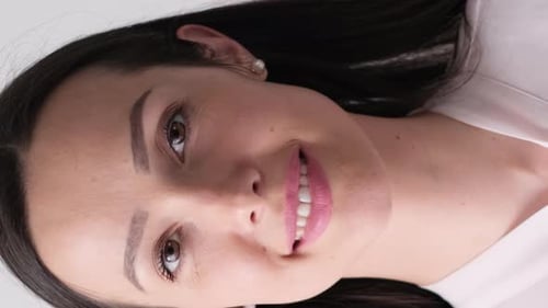 Portrait of a Beautiful Brunette Woman on a Gray Background in the Studio Vertical Video