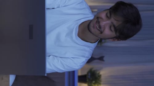Smiling Young Adult Using Laptop Indoors at Night