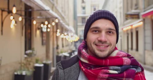Young Caucasian Man Standing on Decorated Street Smiling to the Camera Christmas Mood Concept