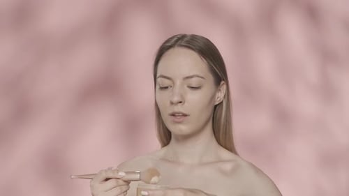 A Beautiful Seminude Woman Dips Her Makeup Brush Into a Jar of Powder Woman Smiling Blowing Off
