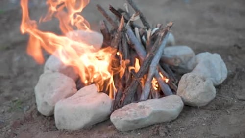 campfire made from wood and a surrounded by small rocks, shot with slow motion in a selective focus