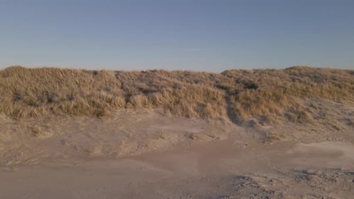 Sandy beach and dunes on ocean coastline, aerial side fly cinematic shot