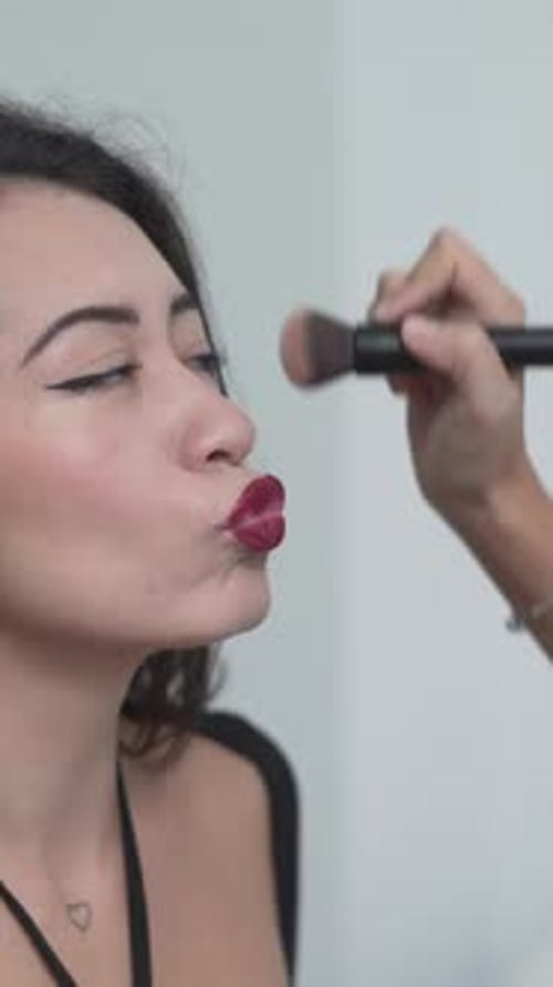 Cropped View Of Female Makeup Artist Applying Finishing Touches To Model Medium Closeup Shot