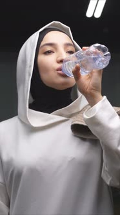A Muslim Woman Drinks Water in the Gym to Feel Good