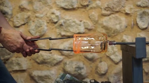 Man Shaping Molten Glass with Tools in Workshop