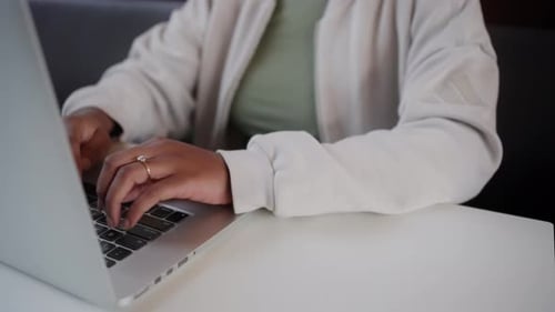 Woman Typing on Laptop Keyboard at a Table