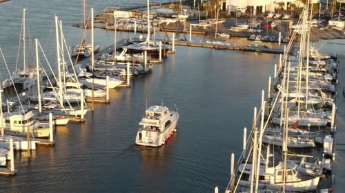 Luxury Motor Yacht At Marina Passing By Moored Boats At Dusk. - aerial
