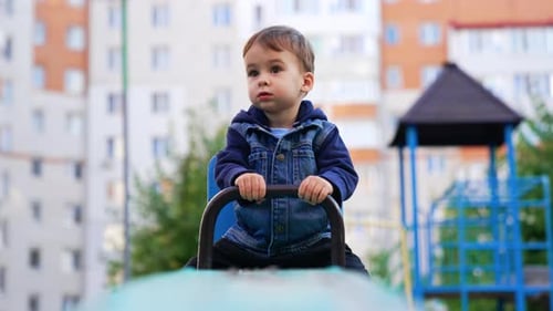 Calm little toddler boy sitting on the seesaw.