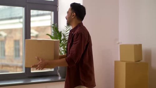 Man Carrying Cardboard Box Moving Into New Home