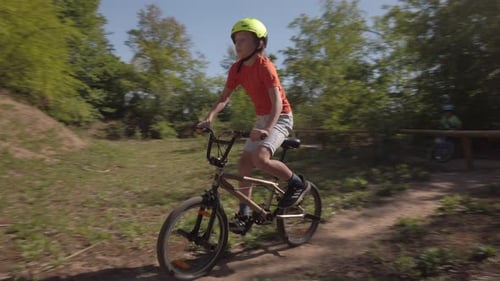Schoolkid in Slowmotion riding bike in a park riding up over the hump in Germany