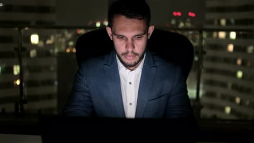 Man Working Late in City Office at Night