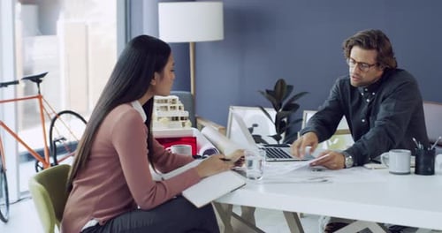 4k video footage of two young architects using a laptop while working together in a modern office