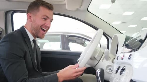 Happy Man Driving a New Luxury Electric Car in a Car Showroom The Buyer Chooses a New Car