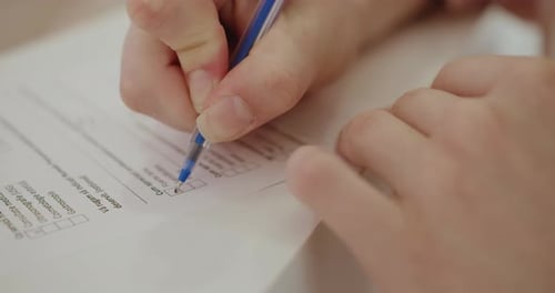 CloseUp View of Hand Writing Checkboxes on a White Form