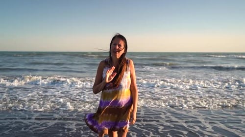 Mujer solitaria en la playa despidiéndose mientras camina de regreso hacia el mar. Concepto suicida. Dolly