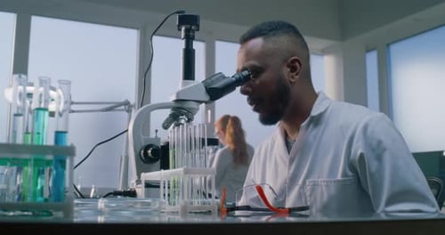 Serious Scientist Working With Microscope In Laboratory