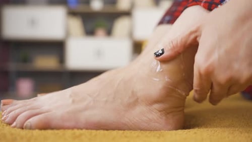 Woman applying cream to her ankle.