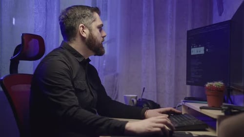 Caucasian Male Freelancer Works at a Computer at Home