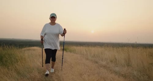 Woman Hiking with Poles in Grassy Field