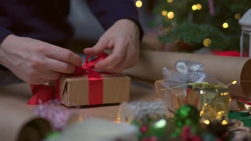 Hands Tie Red Ribbon On Christmas Gift