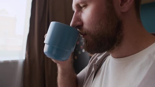 Man drinking from a blue mug indoors