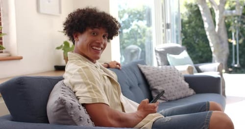 Smiling Young Adult Relaxing with Phone at Home