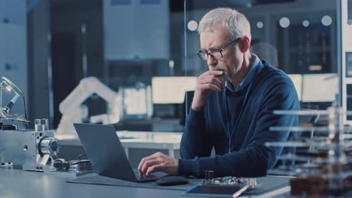 Professional Electronics Design Engineer Wearing Glasses Works on Computer in Research Facility. In