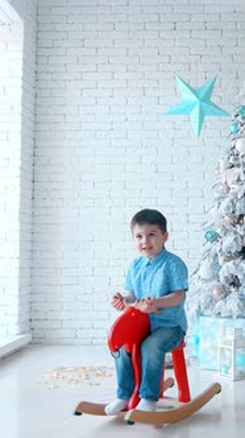Young Boy Joyfully Riding a Rocking Horse in a Bright Room Decorated for the Holidays