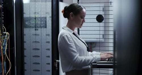 Woman Working on Laptop in Server Room