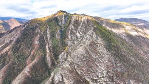 Sunlit mountains with autumn forest and rocky slopes