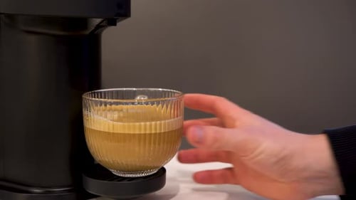 Hand Takes Glass Coffee Mug from Machine