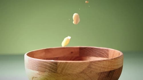 Slow Motion Shot Of Dried Fruits Falling In wooden Bowl In Green Background